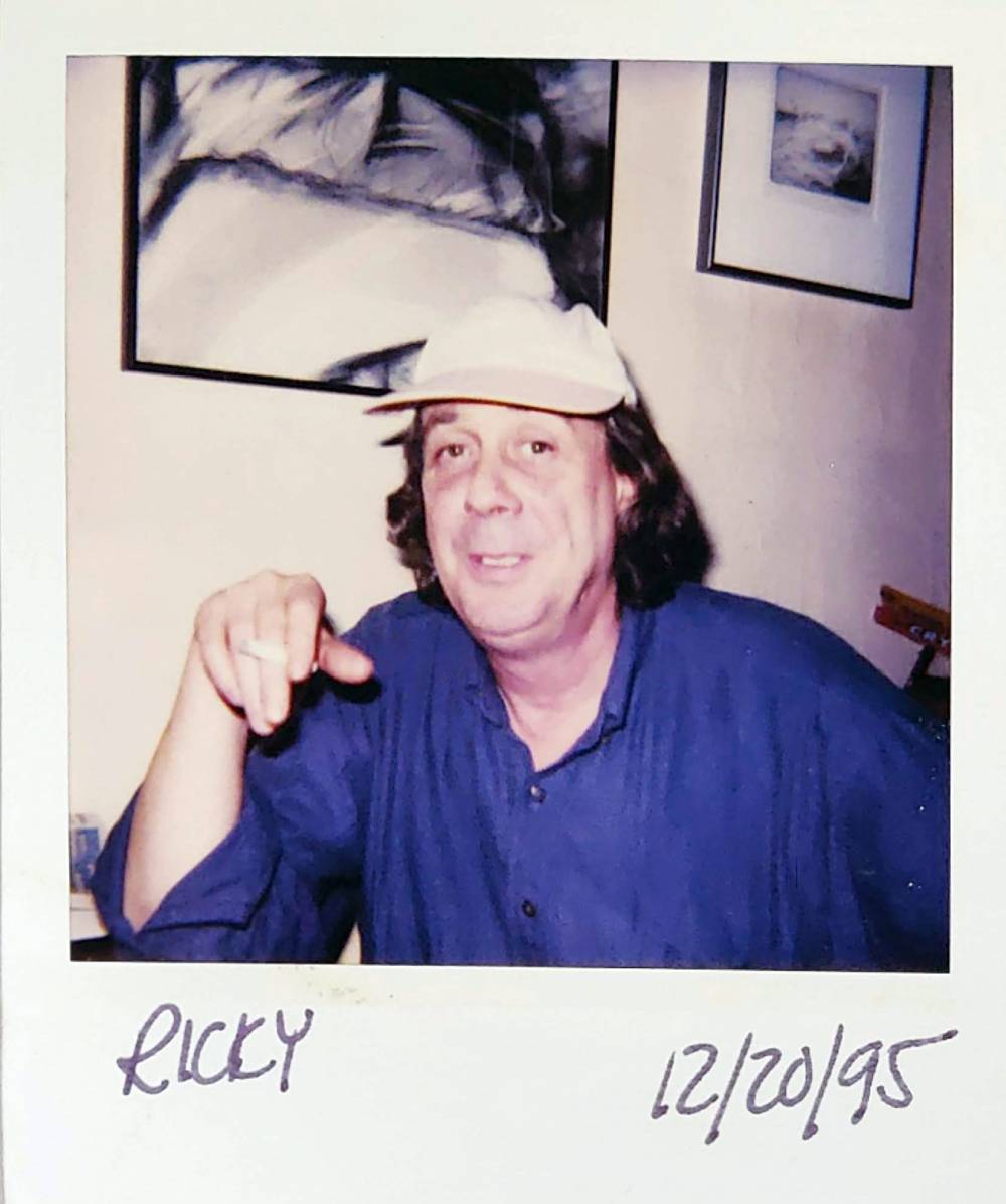 FL Decker wearing a hat with artwork behind him in a scanned Polaroid picture