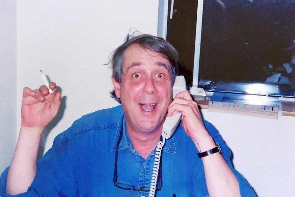 FL Decker in an office with a phone to his ear, a cigarette in his hand, and an excited expression