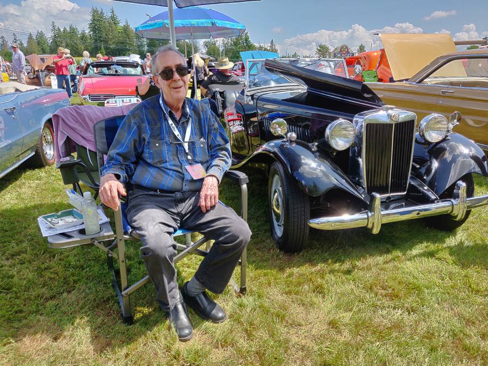 FL Decker sitting in a camping chair next to his MGTD that is parked in the grass